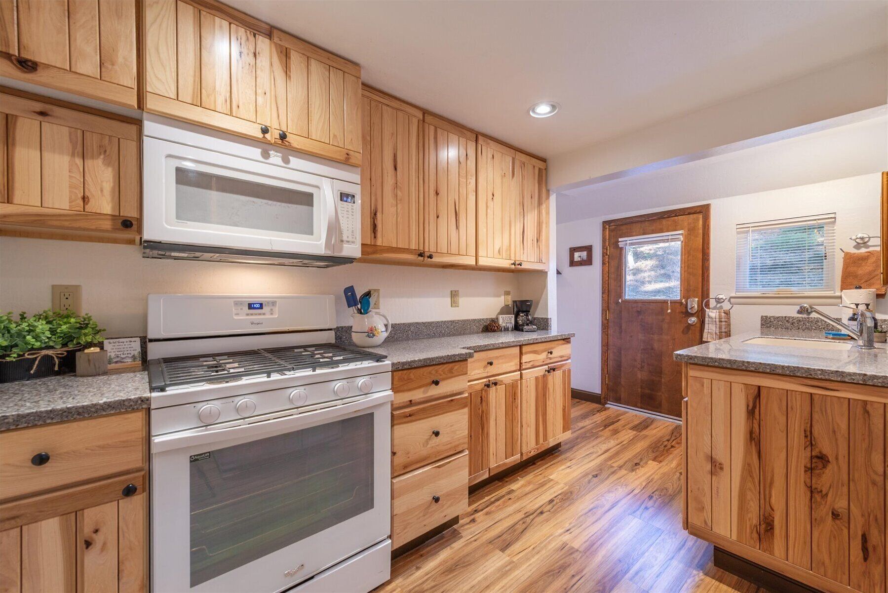 A kitchen with wooden cabinets, a microwave, a stove, and a sink.