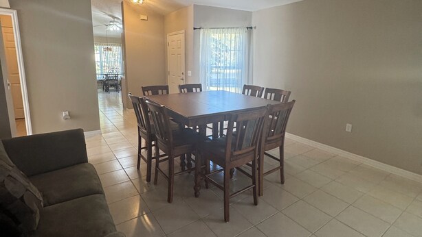 A spacious living area with a dining table surrounded by chairs, a sofa, and a ceiling fan. - Welcome to resort style living in Kissimmee! (Kissimmee)