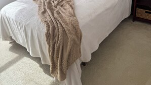A neatly made bed with a beige blanket, a wooden headboard, and two bedside tables with lamps. - Welcome to resort style living in Kissimmee! (Kissimmee)