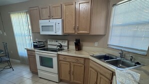 A kitchen with wooden cabinets, a microwave, stove, and a sink. - Welcome to resort style living in Kissimmee! (Kissimmee)