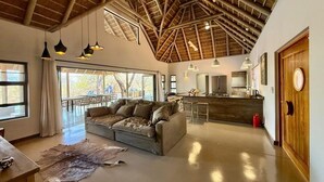 A spacious living area with a high ceiling, a sofa, a dining table, and a kitchen area. - Luxury Bush villa for rent in Hoedspruit, near Kruger National Park (Hoedspruit)