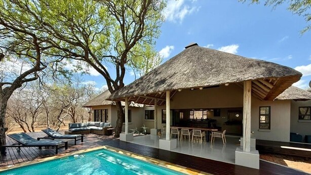 A poolside area with a thatched-roof structure, lounge chairs, and a bar. - Luxury Bush villa for rent in Hoedspruit, near Kruger National Park (Hoedspruit)
