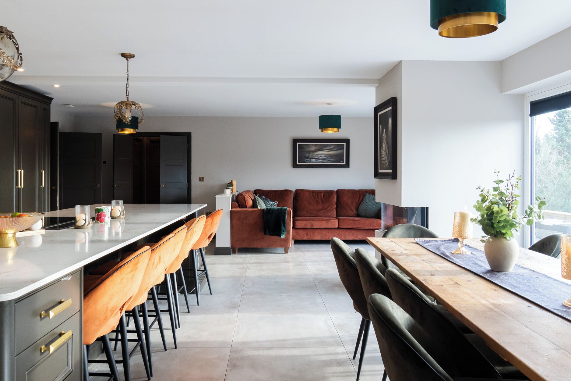 A modern kitchen with a central island, dark cabinets, and a dining area with a wooden table and chairs.
