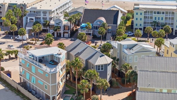 A coastal hotel with multiple buildings, a swimming pool, and palm trees. - 6 Bedroom IOP Home w/ Community Pool Just Outside | Steps from Beach and Fun (Isle of Palms)