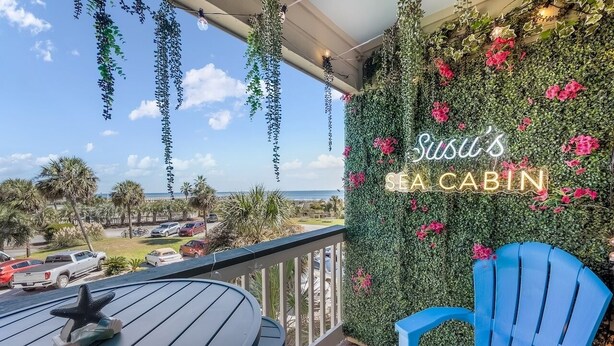 Een balkon met uitzicht op het strand, een neonbord waarop 