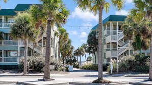 Een strandhotel met meerdere balkons, palmbomen en een heldere lucht.