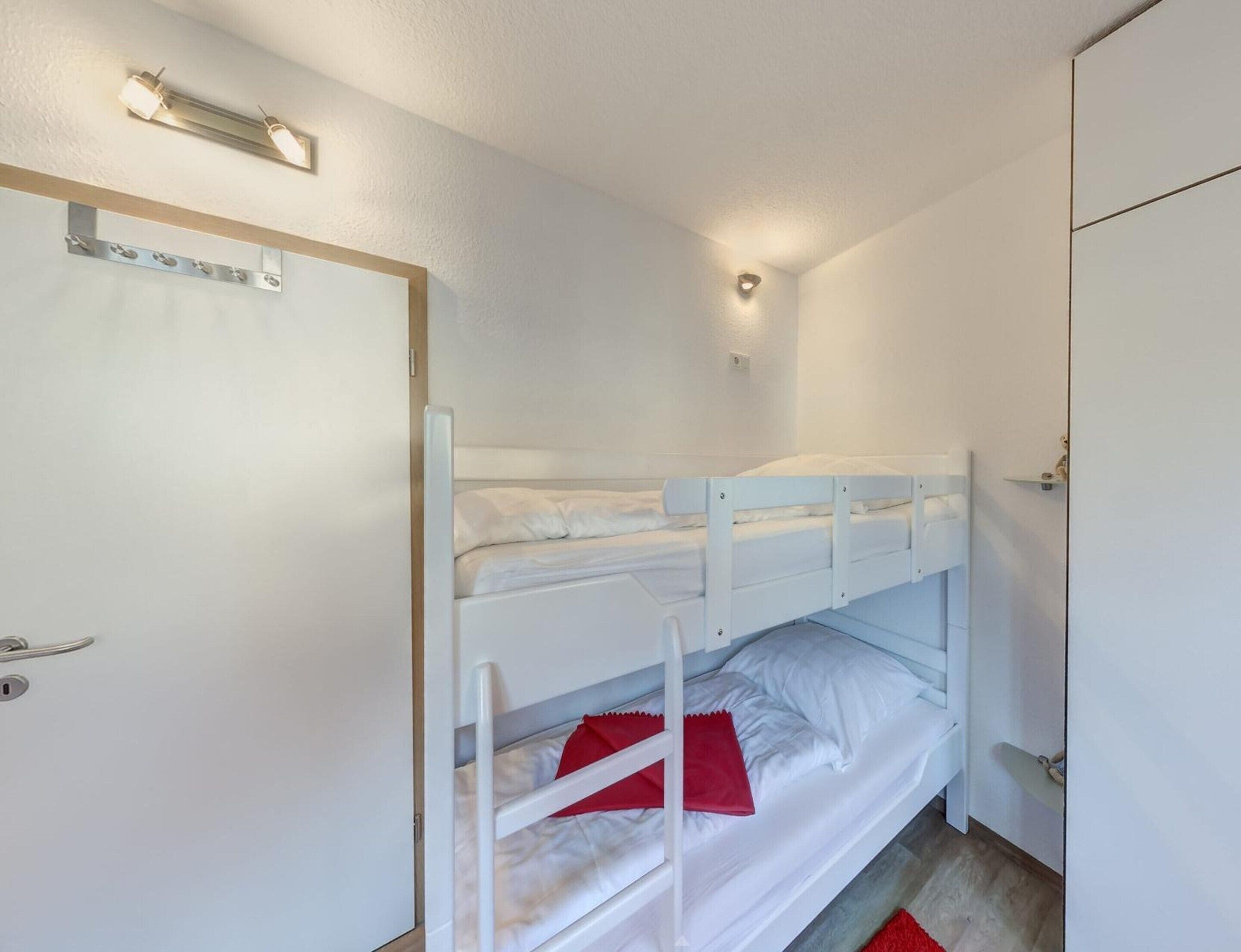 A bunk bed room with a door, a light fixture, and a small shelf.