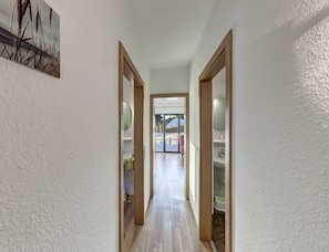 A hallway with wooden doors leading to a bathroom and a view of a patio area. - Grosszugige Ferienwohnung fur bis zu 9 Personen (Butjadingen)