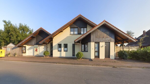 A two-story building with a gabled roof and a small porch. - Grosszugige Ferienwohnung fur bis zu 9 Personen (Butjadingen)