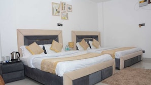 A hotel room with two beds, a coffee maker, and a small table with a kettle. - Pitambara Homestay (Faizabad)