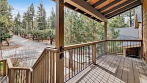 A wooden deck with a railing, overlooking a road and trees. - Brownie Resort Retreat | Walk-to-Ski Snow Summit Duplex Getaway (Big Bear Lake)