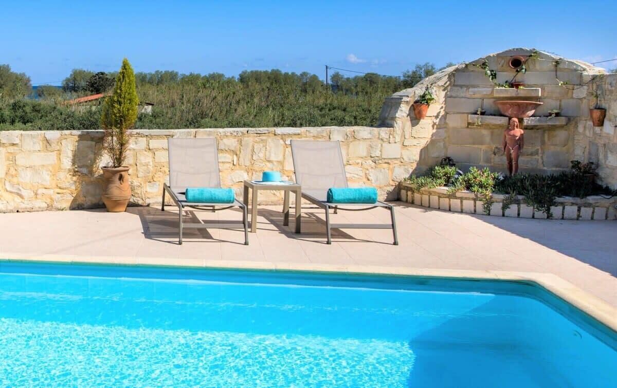 A pool area with lounge chairs and a stone wall.