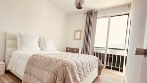 Una camera da letto con un letto, un comodino, una finestra con tende e vista sull'esterno.