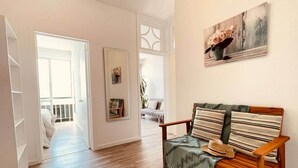Un'ampia zona giorno con pavimento in legno, un divano con cuscini a righe e un quadro appeso al muro.