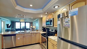 A modern kitchen with stainless steel appliances, wooden cabinets, and a large island. - Edgewater #611 | Beach Access, Pool, Gym, Hot Tub, Grills + More (Miramar Beach)