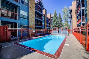 A swimming pool surrounded by multi-story buildings with balconies and a brick facade. - River Mountain Lodge Downtown Condo - Ski In, Mountain Views, Pool/Hot Tub (Breckenridge)