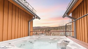 Un jacuzzi con revestimiento de madera y vistas a un paisaje montañoso.