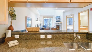 Una cocina con encimeras de granito, un lavamanos de acero inoxidable y armarios de madera.