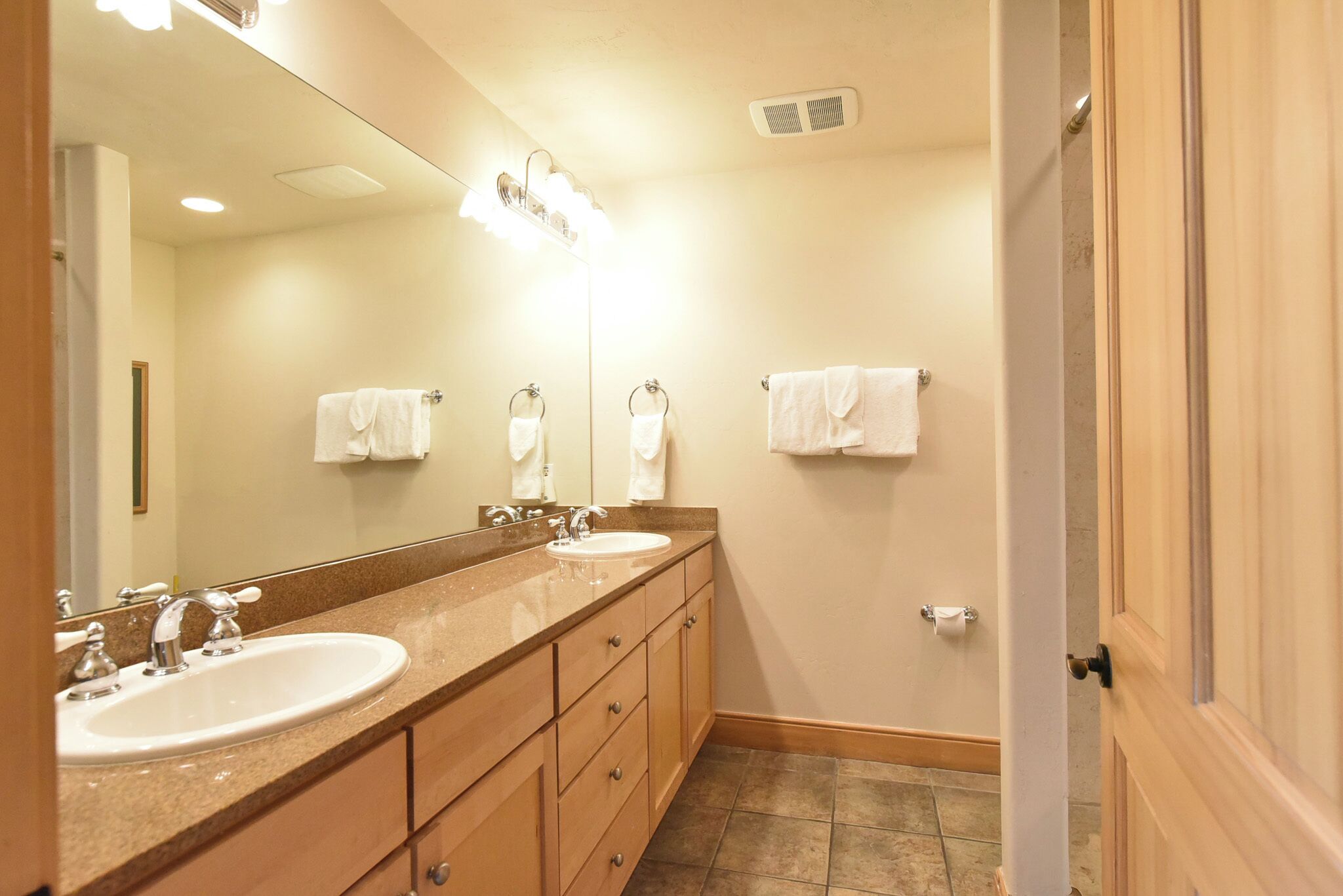A bathroom with two sinks, a large mirror, and a towel rack.