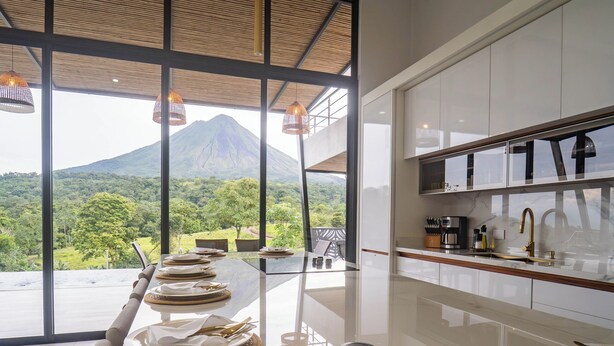 Una cucina moderna con una grande isola, mobili bianchi e vista su una montagna.