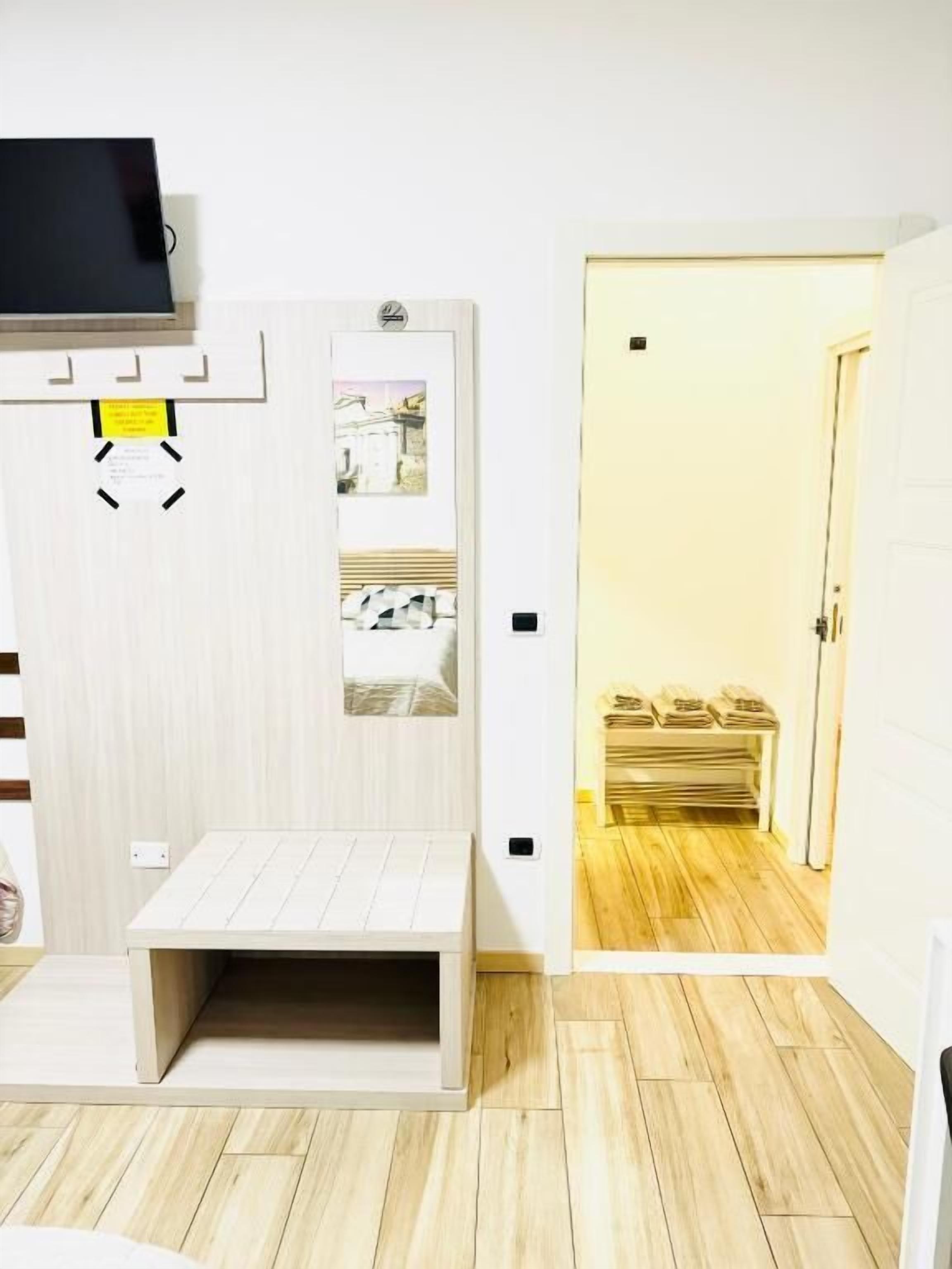 Quarto com uma cama, televisão fixada na parede e porta para um banheiro com toalhas.
