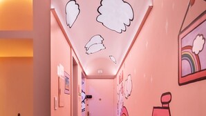 A hallway with a pink wall, white ceiling, and a speckled floor. There are drawings of clouds, a rainbow, and a house on the wall. - COPAN_1401B 3p/0q (São Paulo)