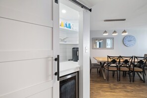 Une cuisine moderne avec des meubles blancs, une machine à café et un coin repas comprenant une table et des chaises en bois.
