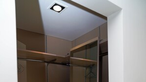 Un dressing accessible sans porte, doté d’étagères ouvertes, d’une tringle à vêtements et d’une porte miroir.