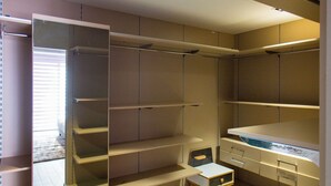 Un dressing accessible sans porte, doté d’étagères ouvertes, d’un petit coin salon et d’une coiffeuse intégrée.