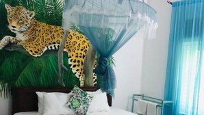 Ein Bett mit blauer Bettdecke, weißen Kissen und einem Kissen mit Leopardenmuster.
