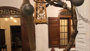 Une pièce comprenant une grande sculpture en forme d’arbre, une petite table avec un vase et une chaise.