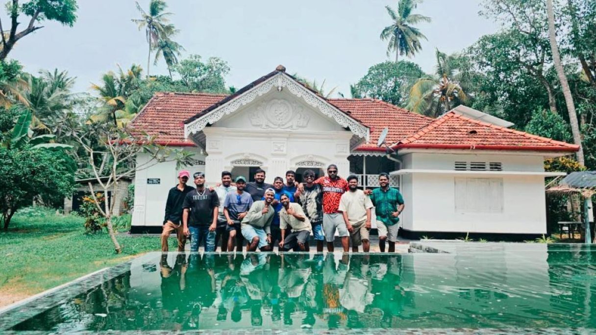 Un groupe de personnes posant devant une maison avec une piscine.