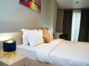 A hotel room with a bed, white bedding, a blue bedside lamp, a painting on the wall, and a window with curtains. - Premium Large Three Bedroom Apartment at Pearl in City (Accra)