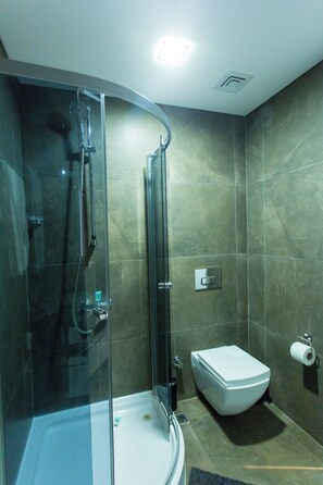 A modern bathroom with a glass-enclosed shower, a white toilet, and a visible hand dryer. - Premium Large Three Bedroom Apartment at Pearl in City (Accra)