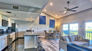 A modern kitchen with a central island, dining area with chairs, and a sofa. - 🐬Waterway Views🌞Quick Walk to Beach🌴Intercoastal #209 - Intercoastal Escape (Indian Shores)