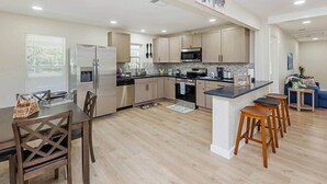 Une cuisine moderne avec des meubles en bois clair, des appareils en acier inoxydable et un îlot central doté de tabourets.
