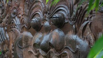 A detailed stone carving with intricate designs and foliage in the foreground.