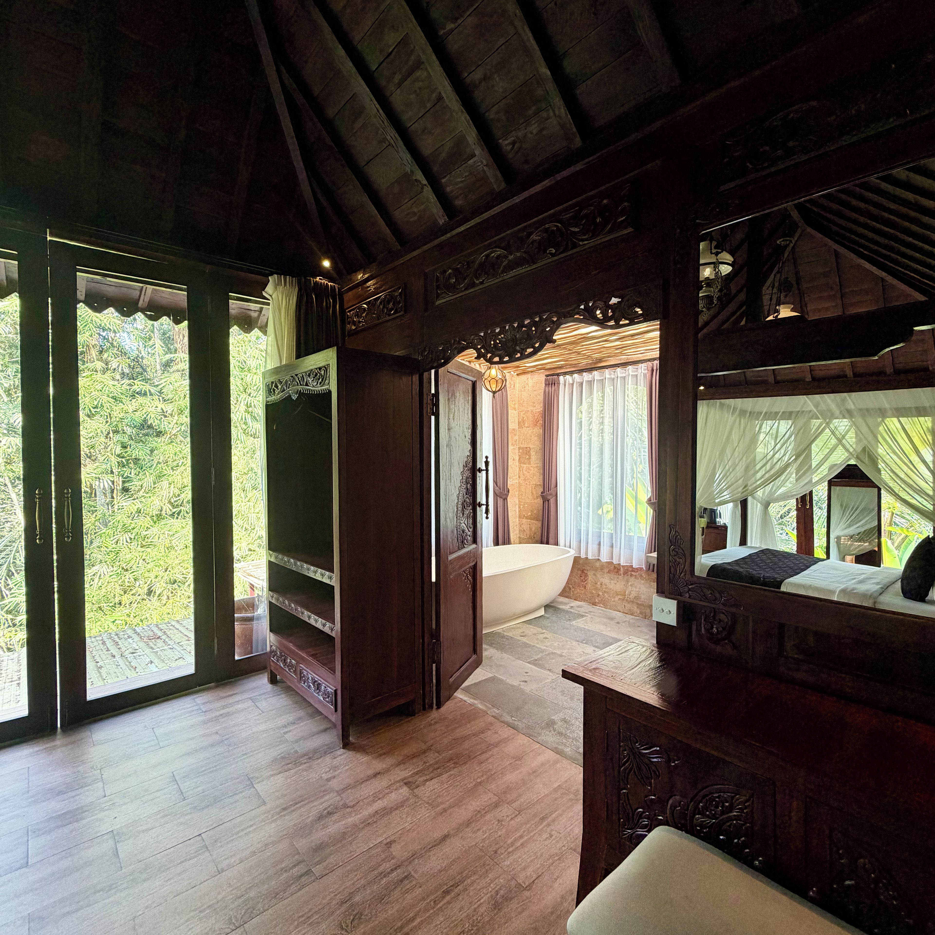 Ein geräumiges Zimmer mit einer großen Badewanne, Holzböden und Blick ins Grüne.