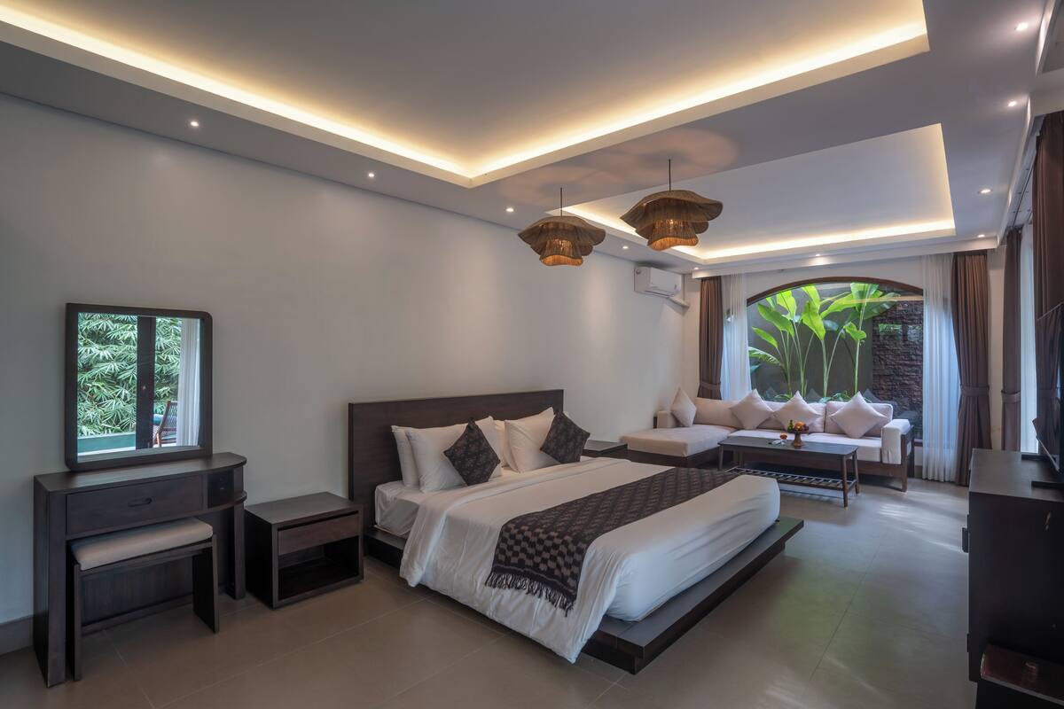 Een moderne slaapkamer met een groot bed, nachtkastjes, een bank en een televisie.