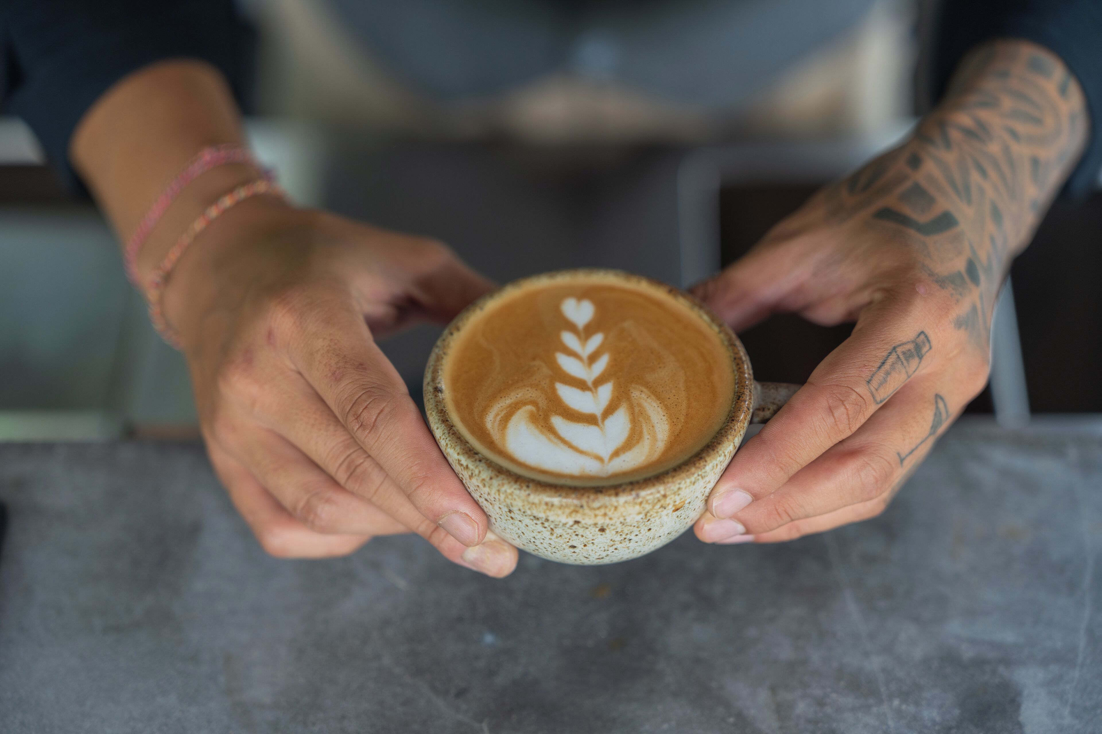 A person holding a cup of coffee with latte art.