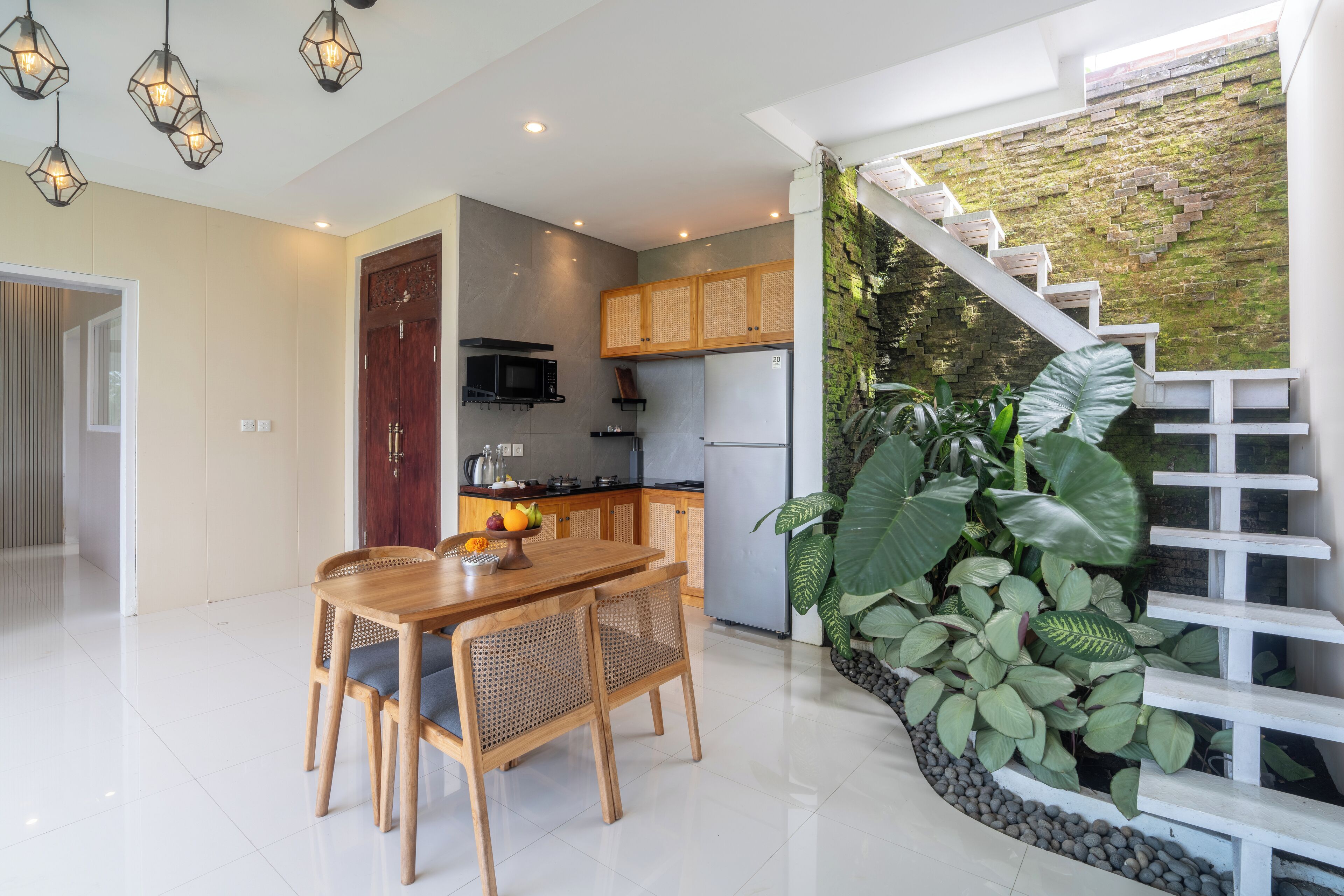 A modern kitchen with a built-in microwave, a refrigerator, and a dining area with a wooden table and chairs.