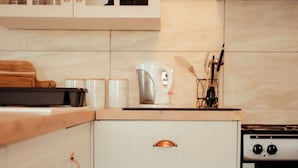 Eine Küche mit weißen Schränken, einer Edelstahl-Dunstabzugshaube, einer Kaffeemaschine und einem Herd.