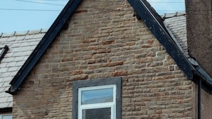 Ein zweistöckiges Steinhaus mit Satteldach und Schornstein.