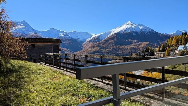 Eine Berglandschaft mit einer Holzhütte und einem Metallgeländer.
