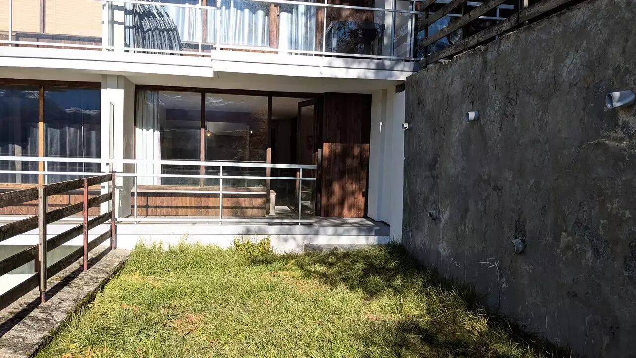 Ein modernes Gebäude mit Balkon, großen Fenstern und einer Betonwand.