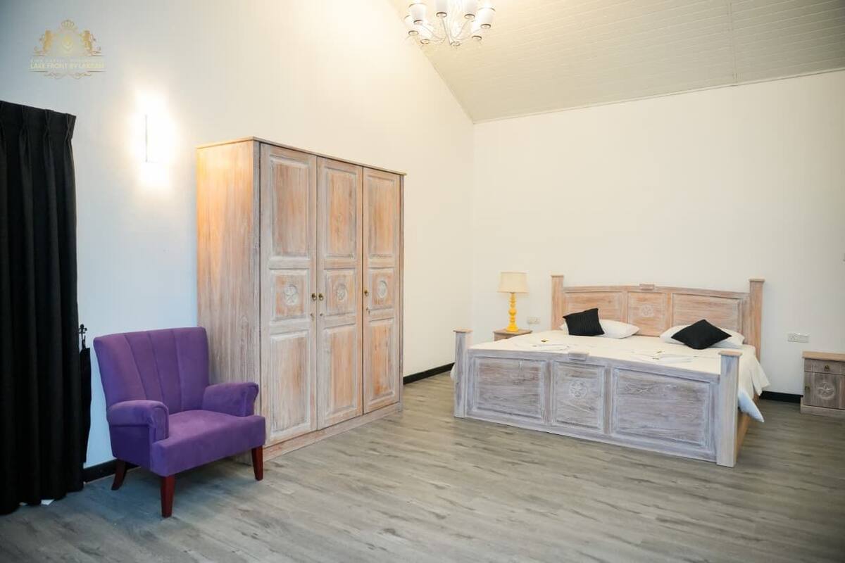 Une chambre à coucher avec un lit, une armoire, une chaise et une lampe.