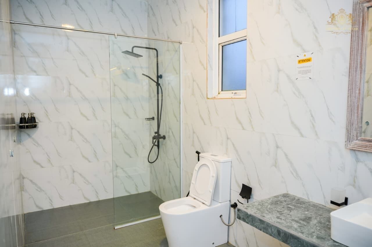 A modern bathroom with a glass-enclosed shower, a white toilet, and a marble wall.