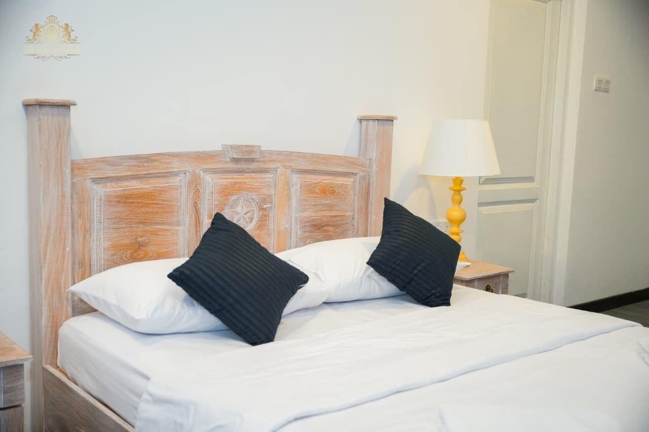 A bed with a wooden headboard, white bedding, and two black pillows.