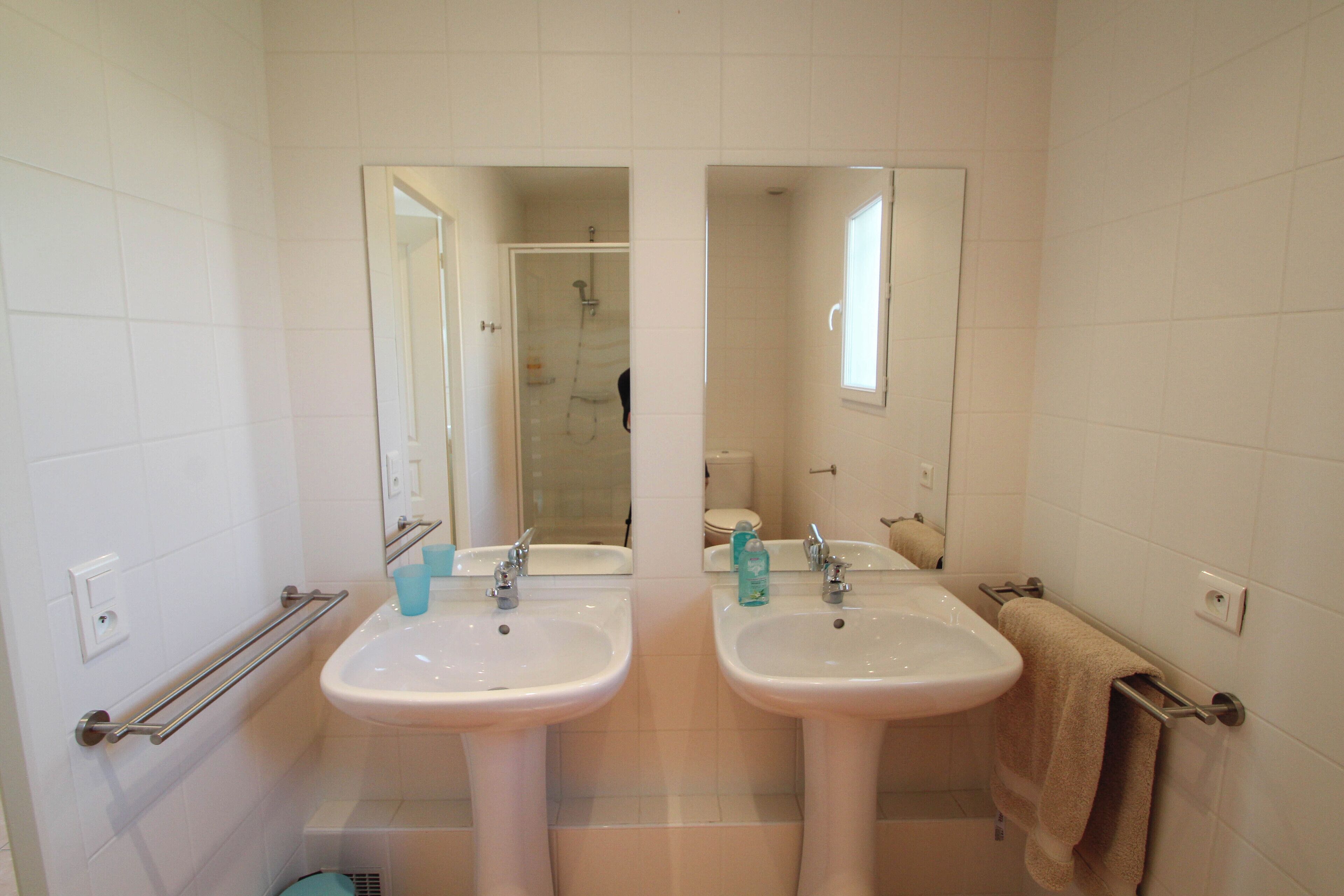 Une salle de bain avec deux lavabos, un porte-serviettes et un miroir.