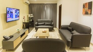 A modern living room with a flat-screen TV, a sofa, a coffee table, and a TV stand. - Spacious Two Bedroom Luxury at Avant Garde (Accra)